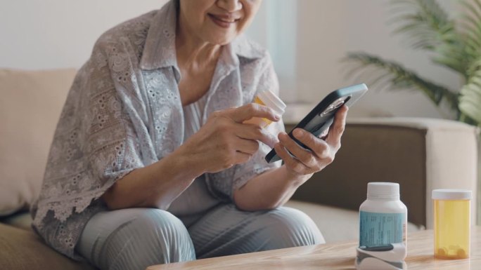 老妇人使用智能手机，感觉很放松，因为她可以在家里自己在线申请买药。