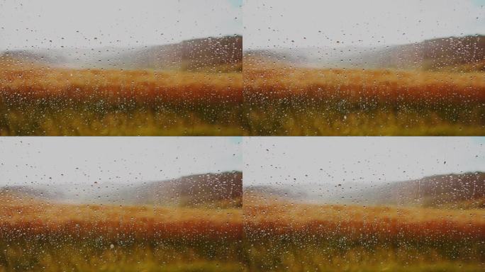 雨滴落在窗户上，可以看到托斯卡纳的乡村风景