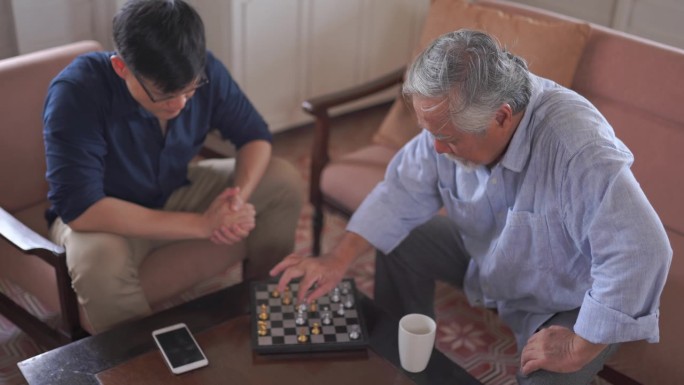 亚洲老人和儿子在家里下棋