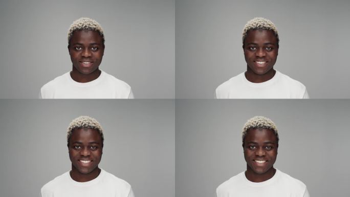 年轻的黑人男子的肖像看着相机在彩色工作室拍摄。成年非洲男孩被孤立在灰色背景上。20多岁的非裔美国人有