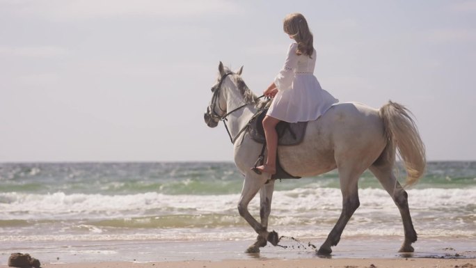 穿白衣的女孩在海边骑马