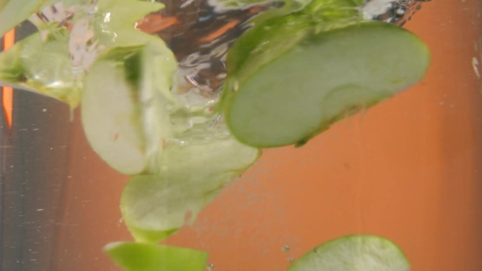 慢动作静态镜头，美味和新鲜的绿苹果块落入一个漩涡的水或水龙卷风和旋转在一个圆圈在水中
