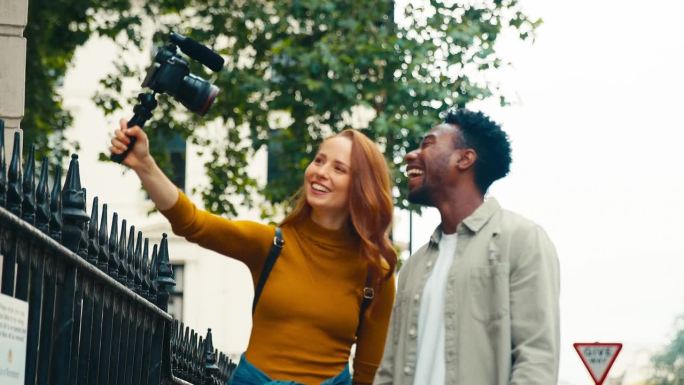 年轻夫妇一起在城市旅行，在三脚架上录制视频