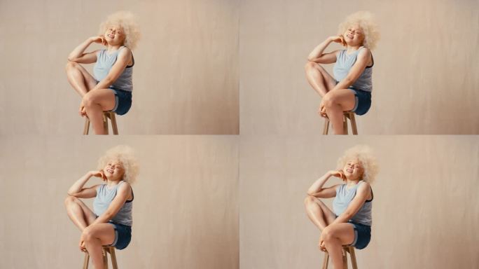 工作室肖像照片随意穿着身体阳性白化病妇女坐在凳子上