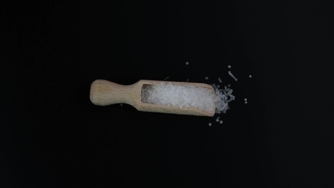 味精、味精粉放在木勺里。4K视频，旋转。中国盐，食品添加剂E621用于食品工业。椭圆形白色结晶颗粒。