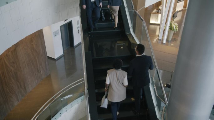 商务人士走上楼梯，在宽敞的酒店大堂交谈的俯视图