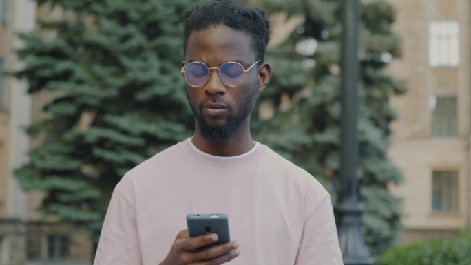 非裔美国人在户外街头使用智能手机触摸屏在线交流的肖像