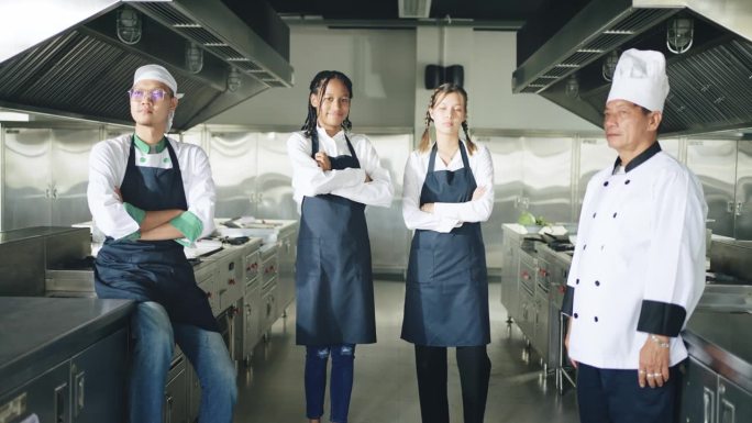 一群快乐的厨师在厨房工作，面对镜头微笑着，双臂交叉。