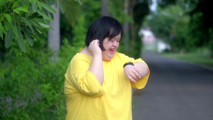 看着时钟，一个患有唐氏综合症的亚洲女孩很高兴。当我在公园里锻炼的时候。
