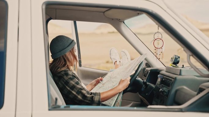 一名妇女在她停在沙漠某处的露营车里看着地图