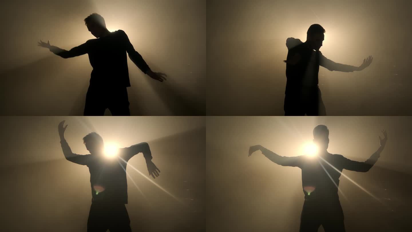美丽的舞蹈背景慢动作，艺术4K概念。一个翩翩起舞的男人的剪影。优雅的男性在摄影棚里跳舞，背景是烟雾中