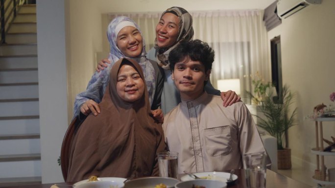 快乐的亚洲穆斯林家庭问候庆祝看着相机拍照回忆斋月晚餐一起在家里。一起庆祝开斋节。开斋节家庭团聚。