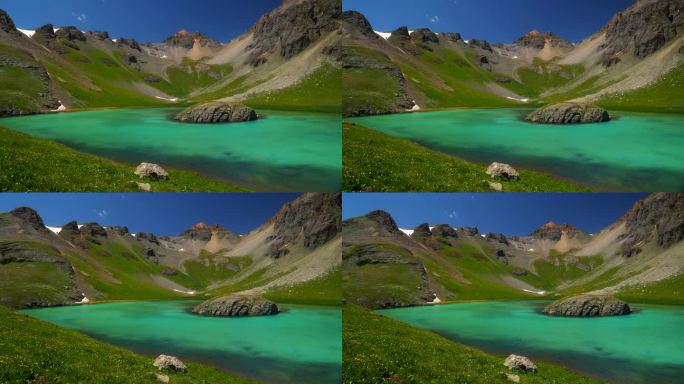 航拍电影无人机冰湖盆地西尔弗顿岛湖夏季水蓝色清澈的水高山苔原令人惊叹的山脉雪野花白天美丽缓慢的锅向左