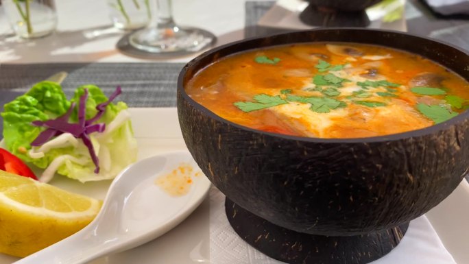 辣味泰式冬阴汤，鸡肉，虾和蔬菜在椰子碗里，美味的泰式料理餐厅，4K拍摄