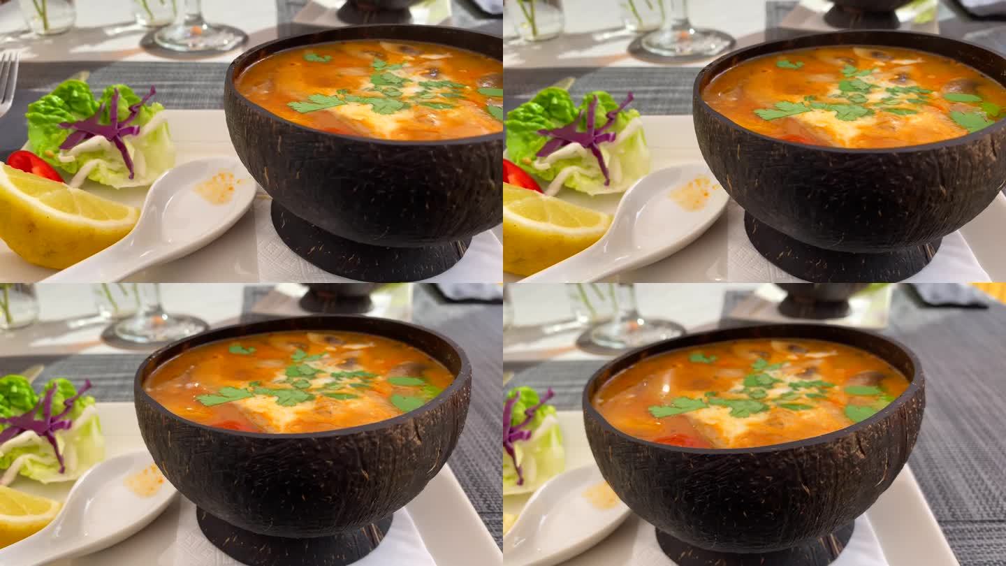 辣味泰式冬阴汤，鸡肉，虾和蔬菜在椰子碗里，美味的泰式料理餐厅，4K拍摄
