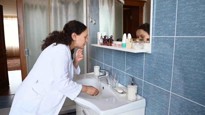 中年孕妇，穿着白色华夫格浴袍，涂洗面奶洗脸