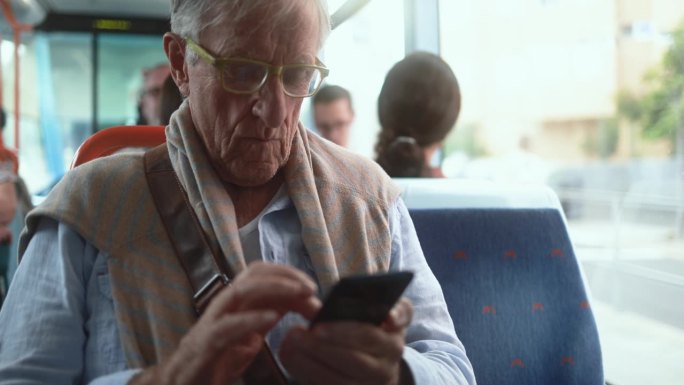 老人坐在电车里玩手机——老年人的生活方式和科技理念