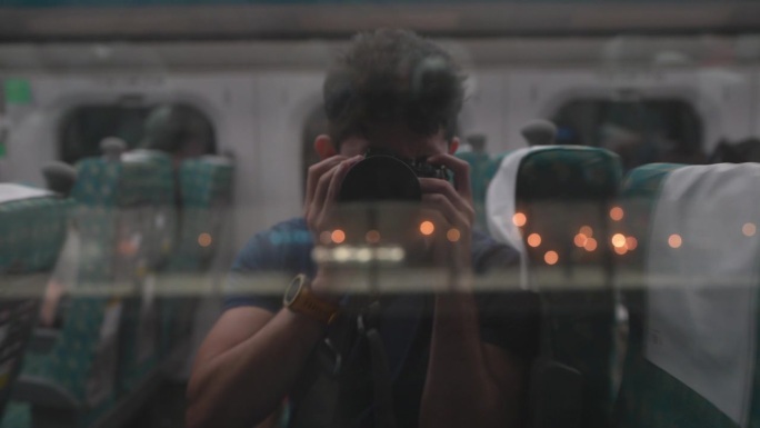 年轻的男性旅行者在火车车窗上拍摄自己的倒影