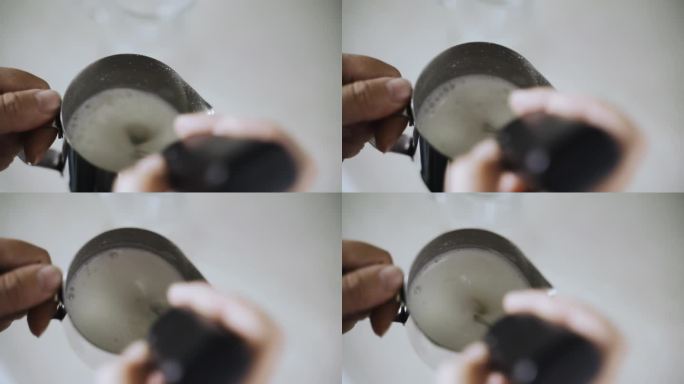 一个女人正在用金属壶搅打奶油和一杯卡布奇诺咖啡。