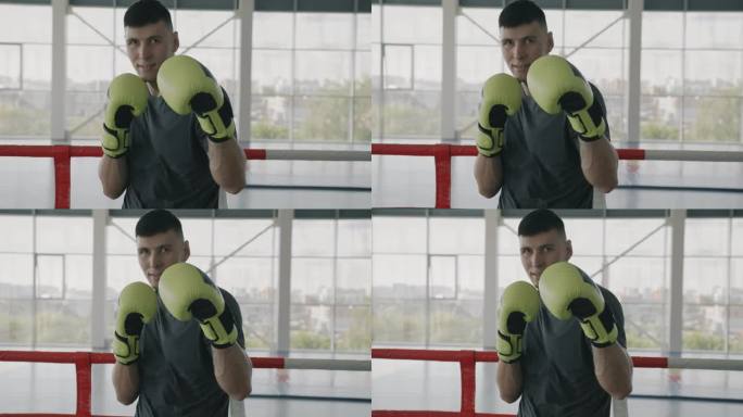 年轻的拳击冠军站在健身房准备战斗的姿势，戴上手套，看着镜头的慢动作肖像