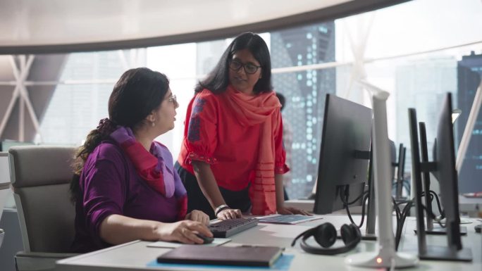 两个不同的同事在忙于公司的团队项目时交谈。南亚女设计师与印度项目经理的对话。创业中的团队合作