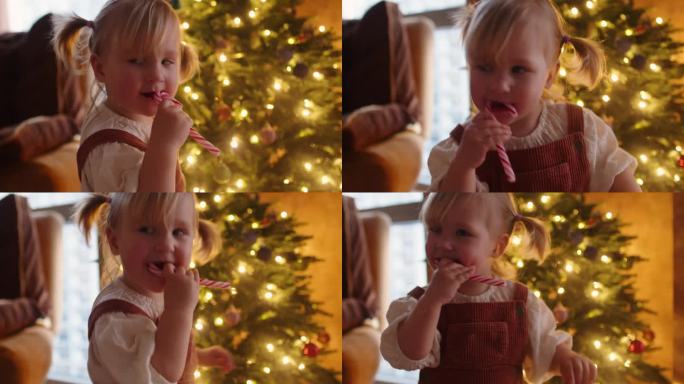 快乐的小女孩在家里圣诞树旁拿着拐杖糖