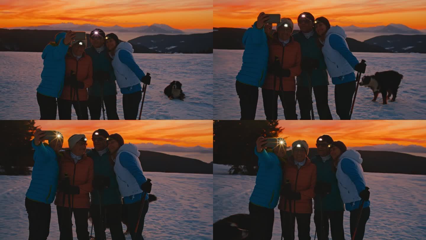 一对老年夫妇和两个已成年的女儿在雪地里用手机自拍，玩得很开心