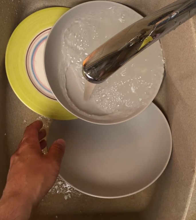 在水槽里用海绵和洗洁精垂直洗碗