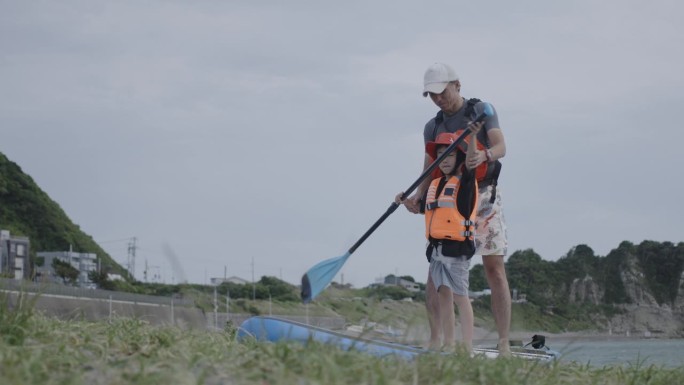 爸爸在宁静的海滩边耐心地教儿子玩桨板