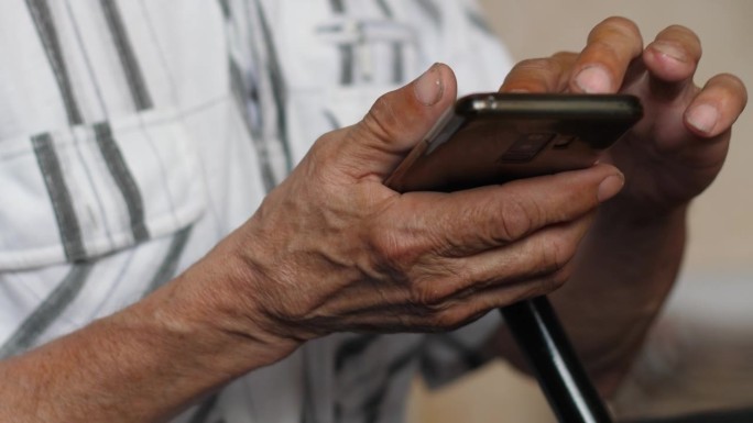老人日常使用智能手机的特写手，老人的生活方式，老人使用小工具，浏览社交网络的新闻