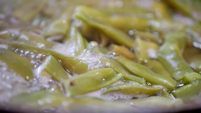 详细说明:边煮边煮四季豆。在一锅法国皮亚通尼豆中，许多沸腾的水在冒泡。