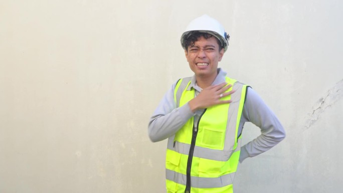 印尼工人穿着背心，戴着白色头盔，摆出痛苦的姿势。