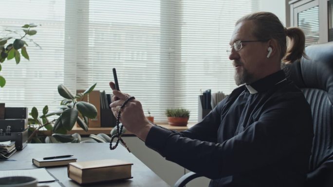成年牧师戴着耳机在视频通话中聊天