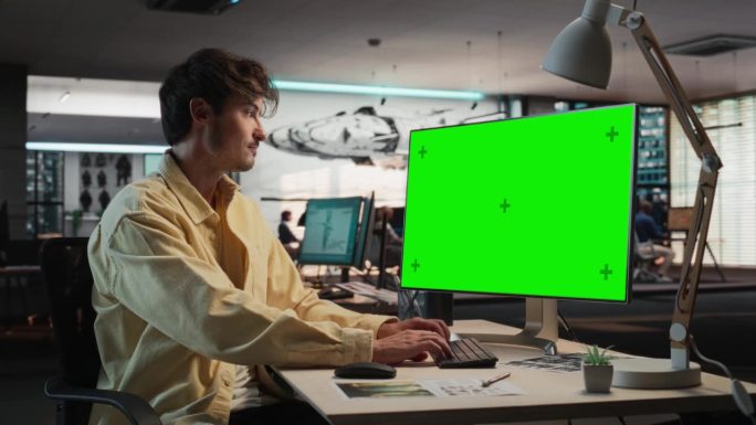 白人男子使用桌面电脑模拟绿屏Chromakey。在游戏设计公司工作的男性概念美工，为新的生存电子游戏