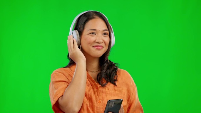 手机，收音机耳机和绿屏上的女人在演播室里被隔离在背景模型上。音乐，聆听和快乐的亚洲人流媒体音频，声音