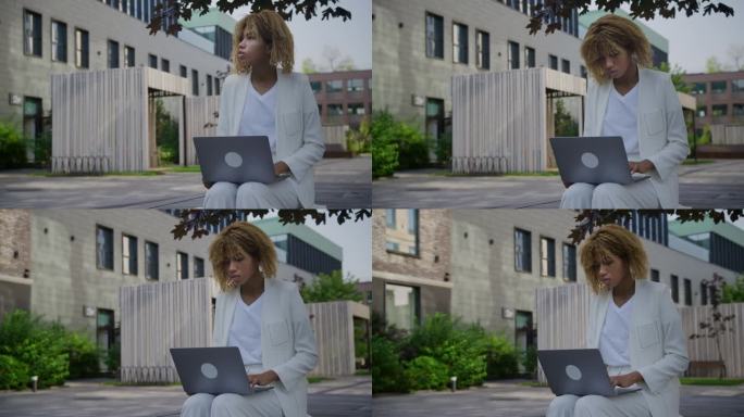 有思想的女人在户外用笔记本电脑工作