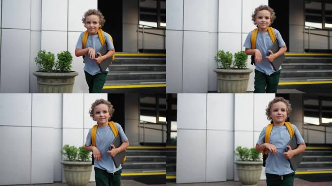 可爱的男生肖像，手里拿着平板电脑，背着书包，放学后走出学校