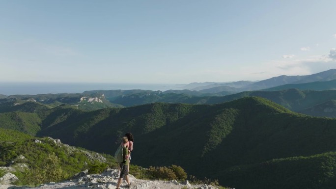 登山夫妇登上山顶欣赏海岸山景