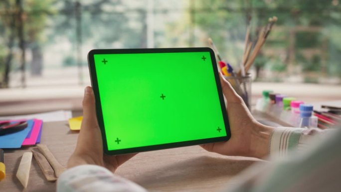 艺术家手持平板设备，看着绿色Chromakey模拟显示屏幕。视频模板与运动跟踪器的数字营销，网站设计