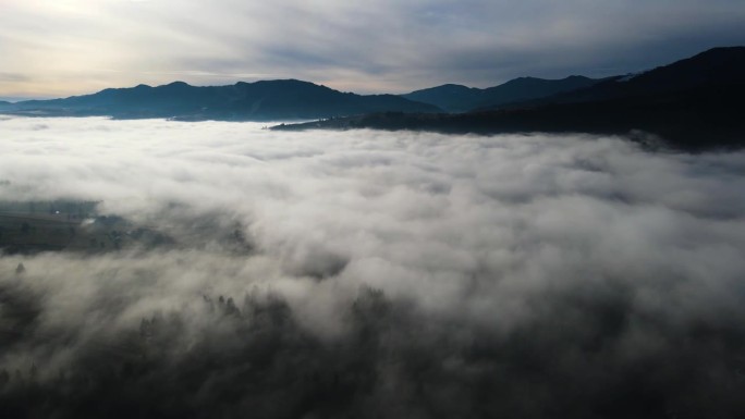 飞过山顶的云层。山峰高耸，清晨日出，自然景观优美