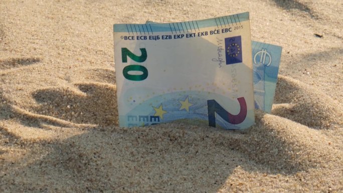 钱，沙滩上的20欧元钞票。概念理财为度假攒钱。旅游假期费用
