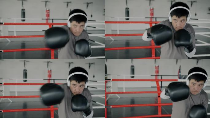 强壮的亚洲拳击手戴着耳机听着音乐，享受着现代健身房的影子搏击