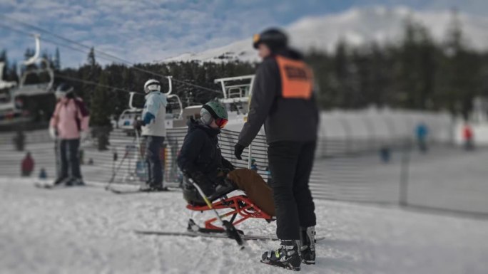 适应性运动员使用坐式滑雪倒车上山