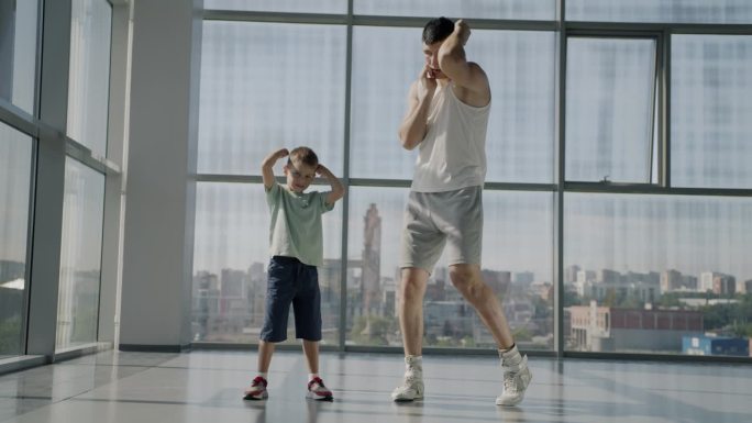 成年男子和小男孩在健身房一起练习拳击动作的慢动作肖像