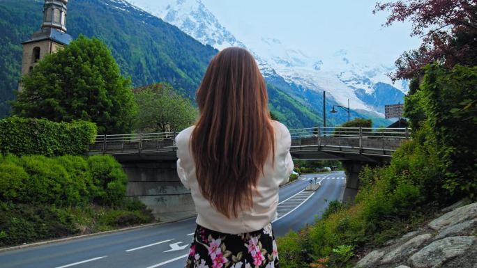 旅游女孩在夏蒙尼以阿尔卑斯山为背景拍照。