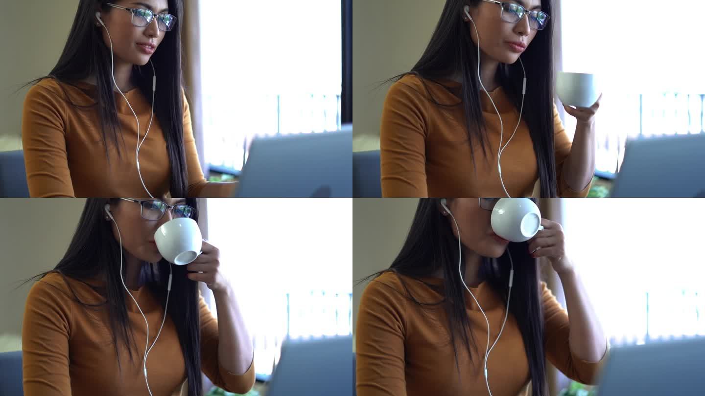 女性在工作或学习时戴着耳机，用笔记本电脑听在线会议。