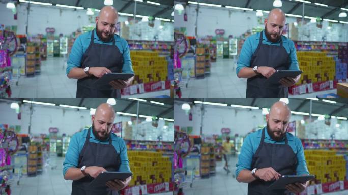 杂货店的巴西员工，戴着围裙，站在连锁超市内，用平板电脑检查库存，专心工作