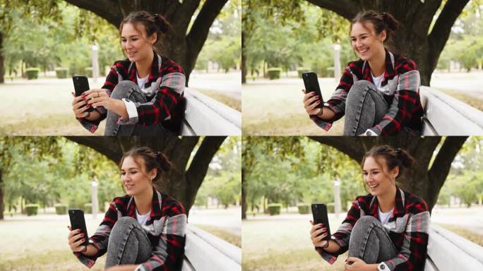自拍，一个微笑的年轻女子在公园的长椅上用手机拍了一张照片，作为她在社交网络上的快乐回忆。