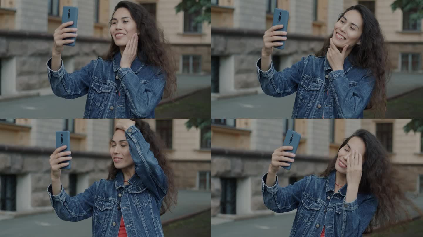 美丽的年轻女子在城市背景下用智能手机自拍的慢动作肖像