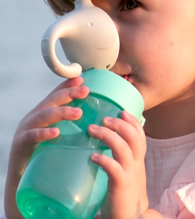 孩子用塑料瓶喝水。地球上水资源短缺问题的概念。水资源短缺问题，地球上的生活方式概念。孩子在大自然中从